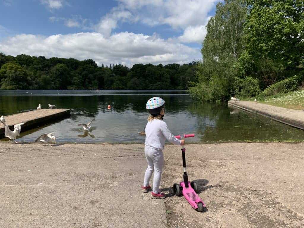 Child with scooter by lake at Decoy Park in Newton Abbot, Devon