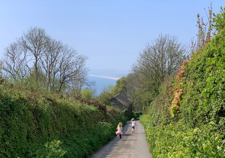 Children running down a Devon country lane towards the sea