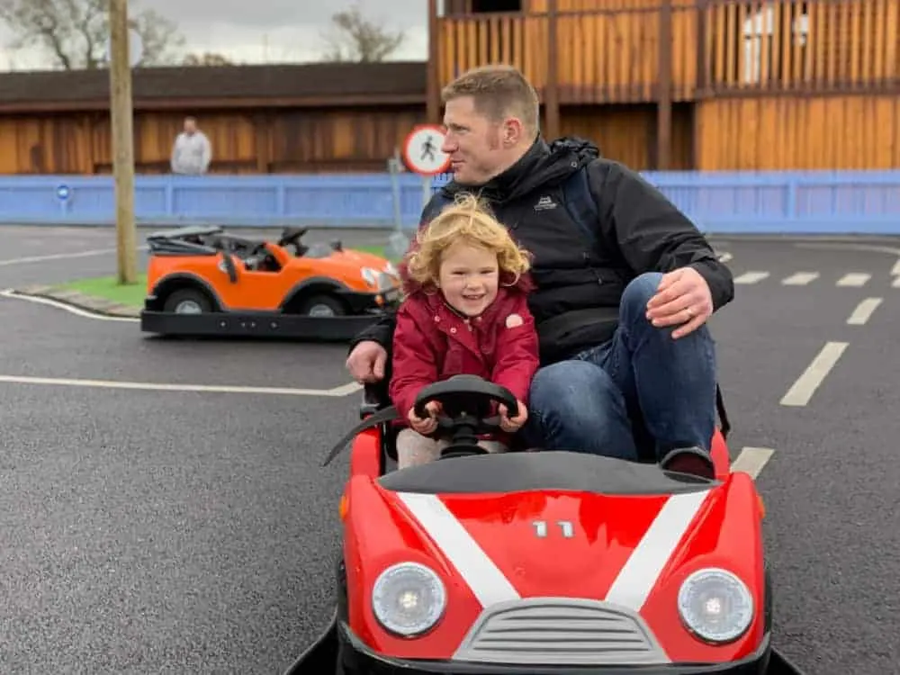 Toddler in car at driving school at Crealy theme park, Devon