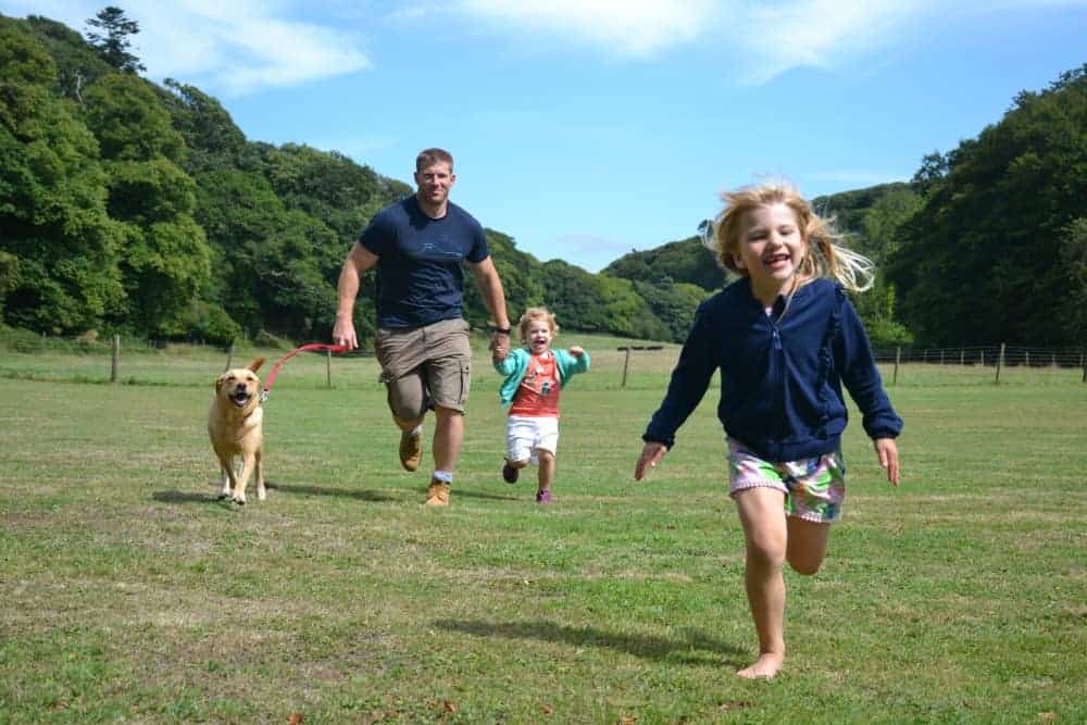 Family with dog running across the lawn at Hartland Abbey in Devon
