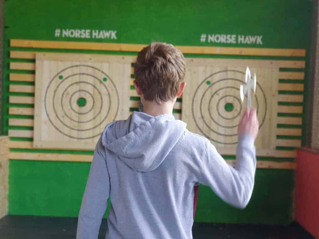 Teenager preparing to throw an axe at a target board