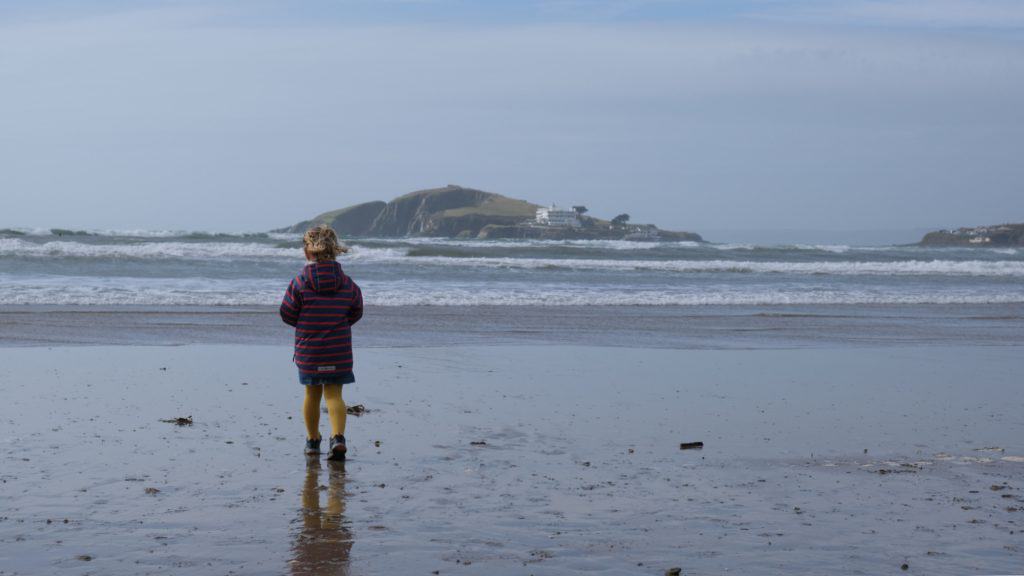 Child walking on sand at Bantham Beach overlooking Burgh Island