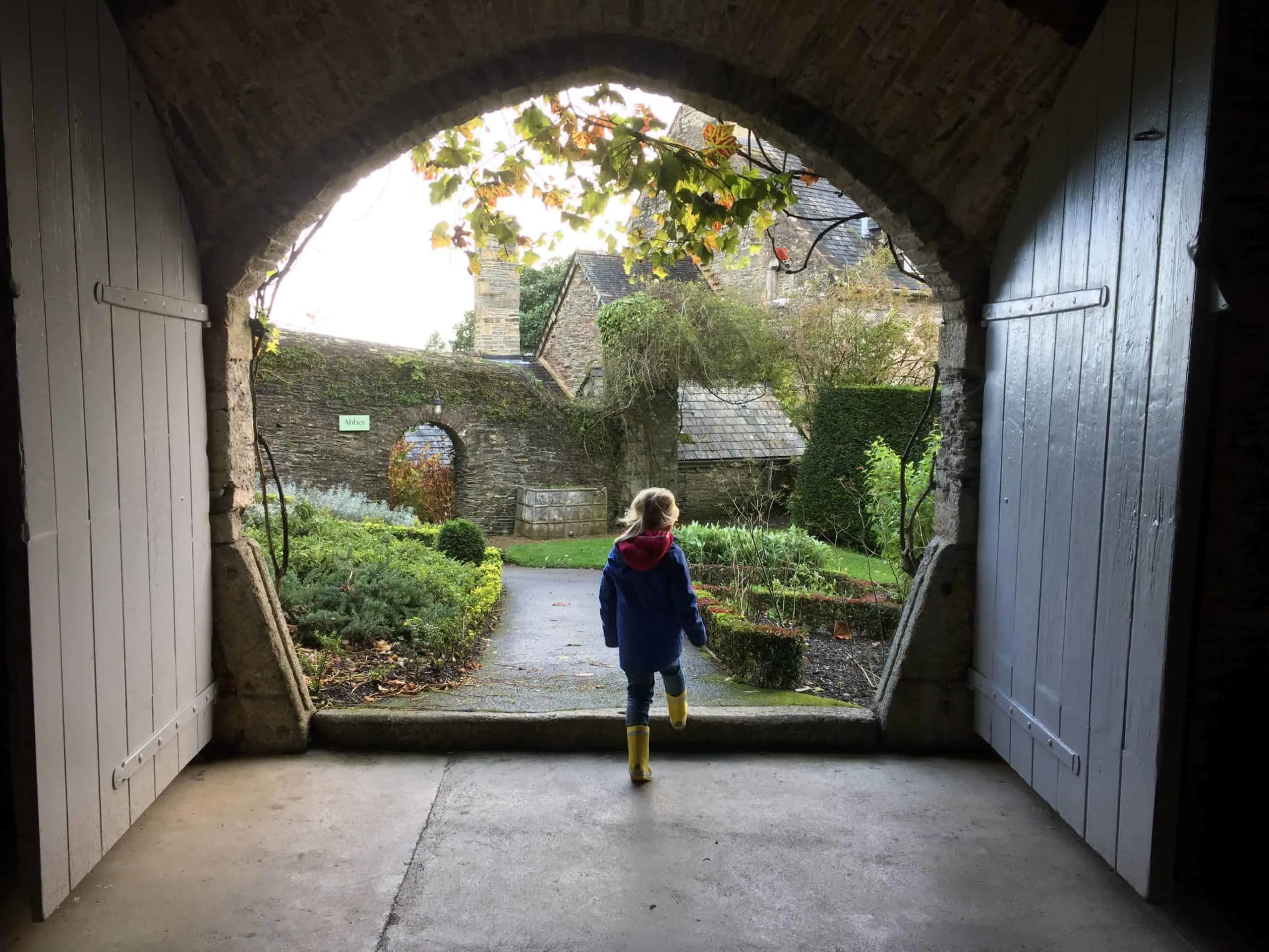 Child walking through doorway into garden at Buckland Abbey in Devon