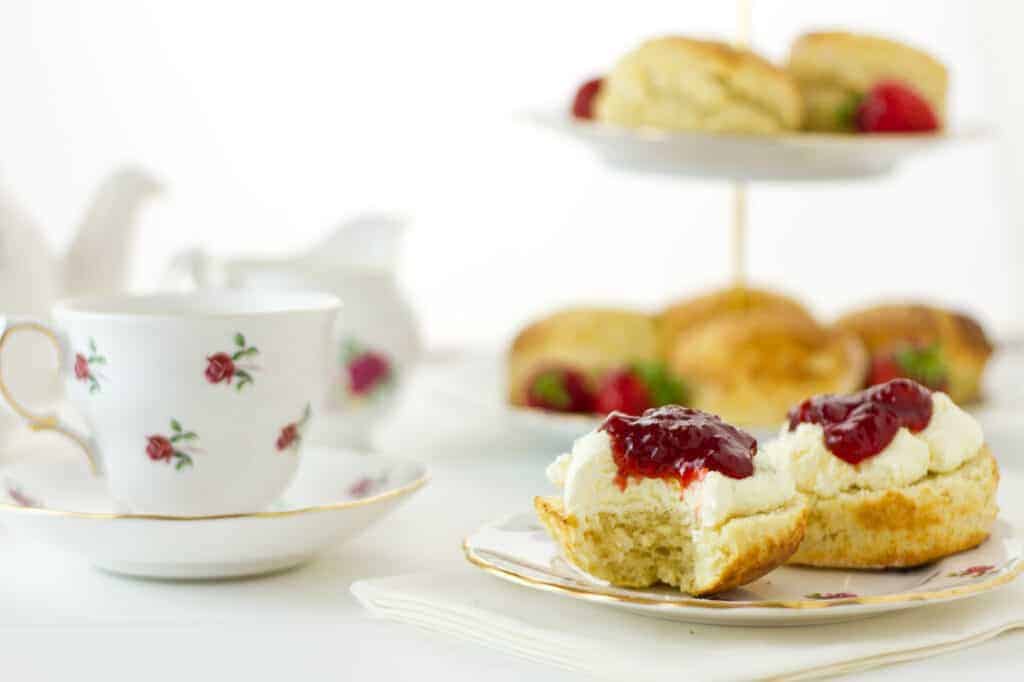 English Cream tea scene with scones, Devonshire style, with a bite taken out.