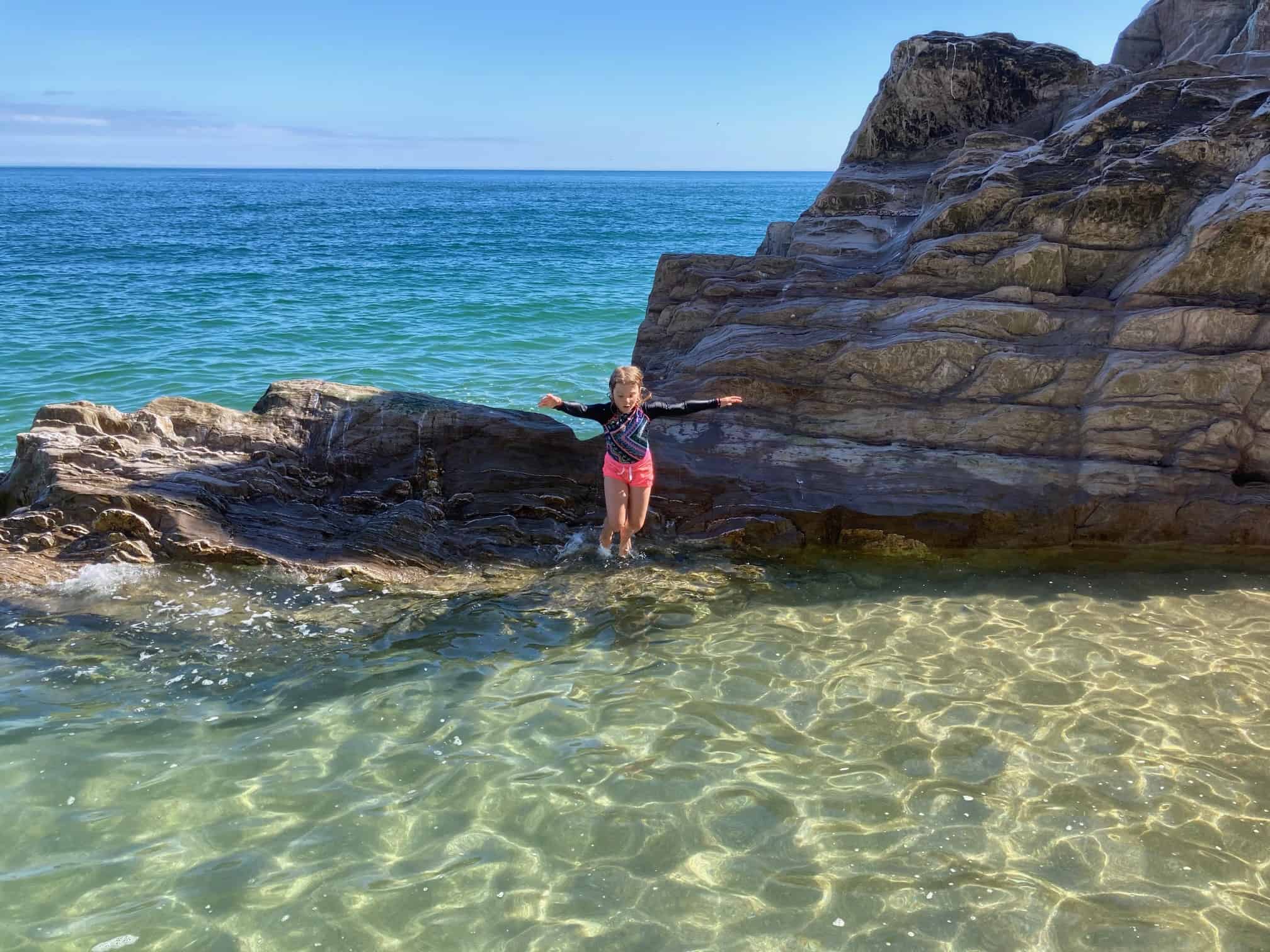 Child jumping into rock pool on Devon beach