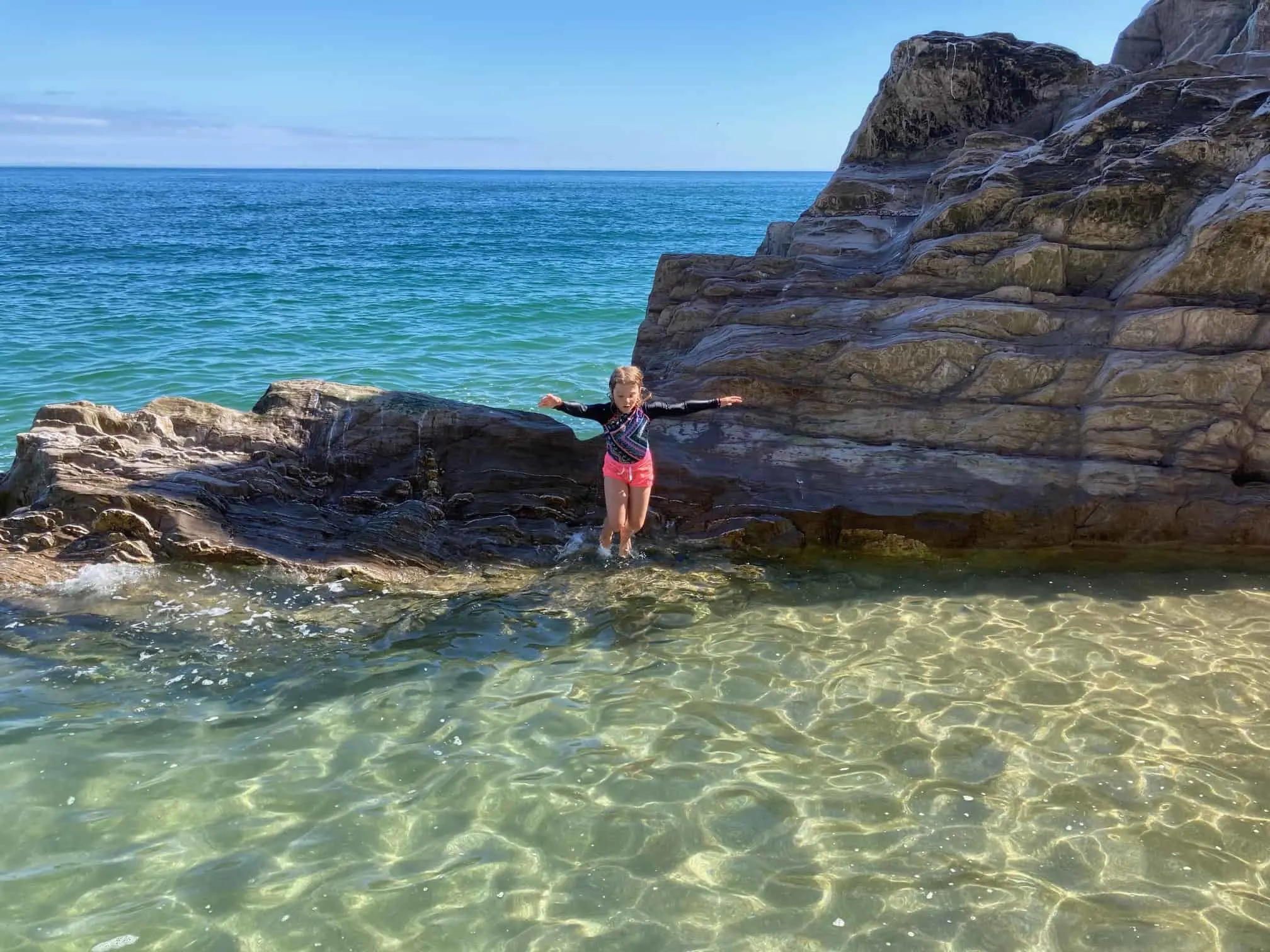 Child jumping into rock pool on Devon beach