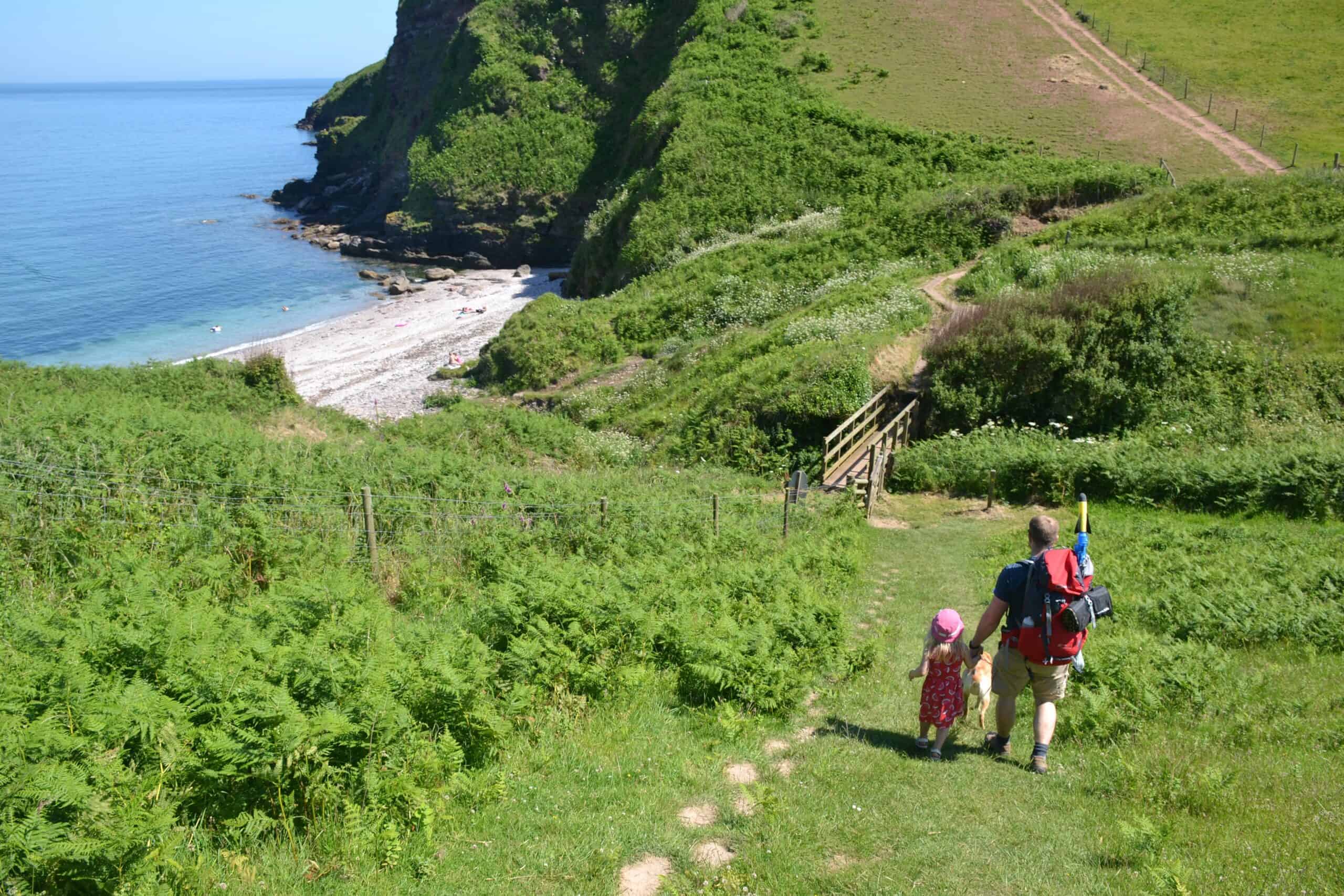 Family walking down hill to beach