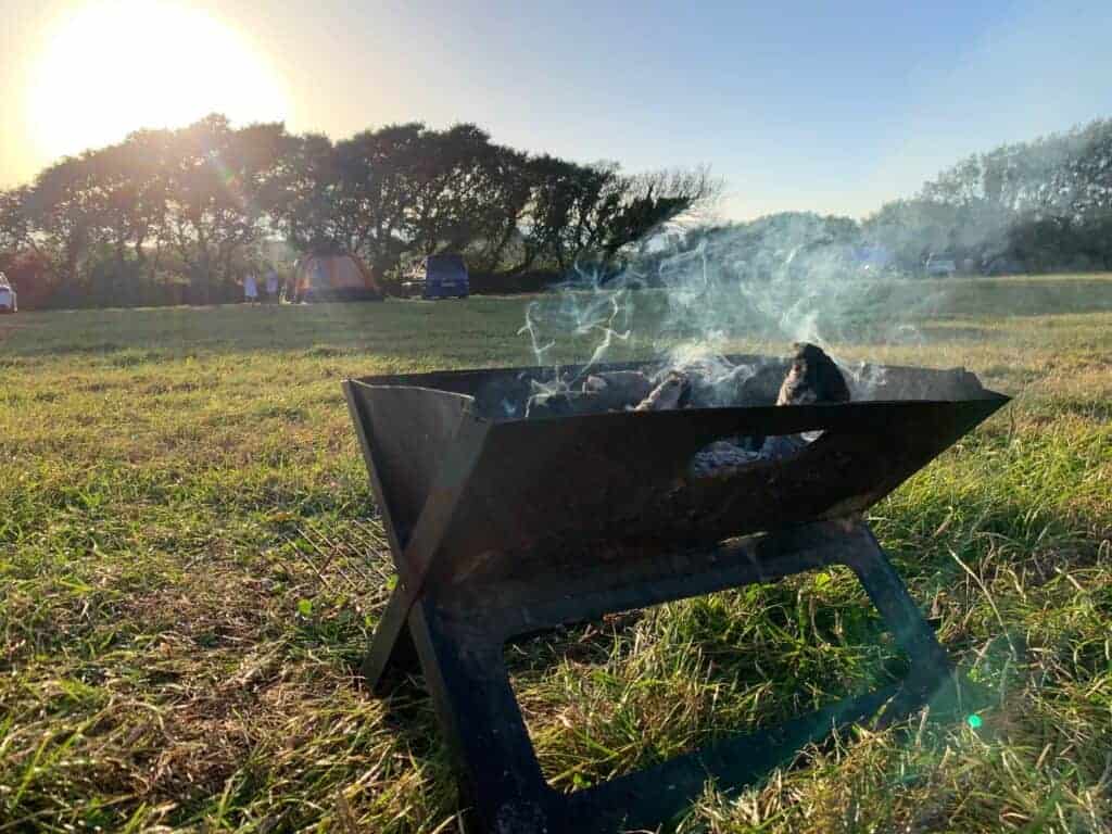 Smoking fire pit at sunset in camping field