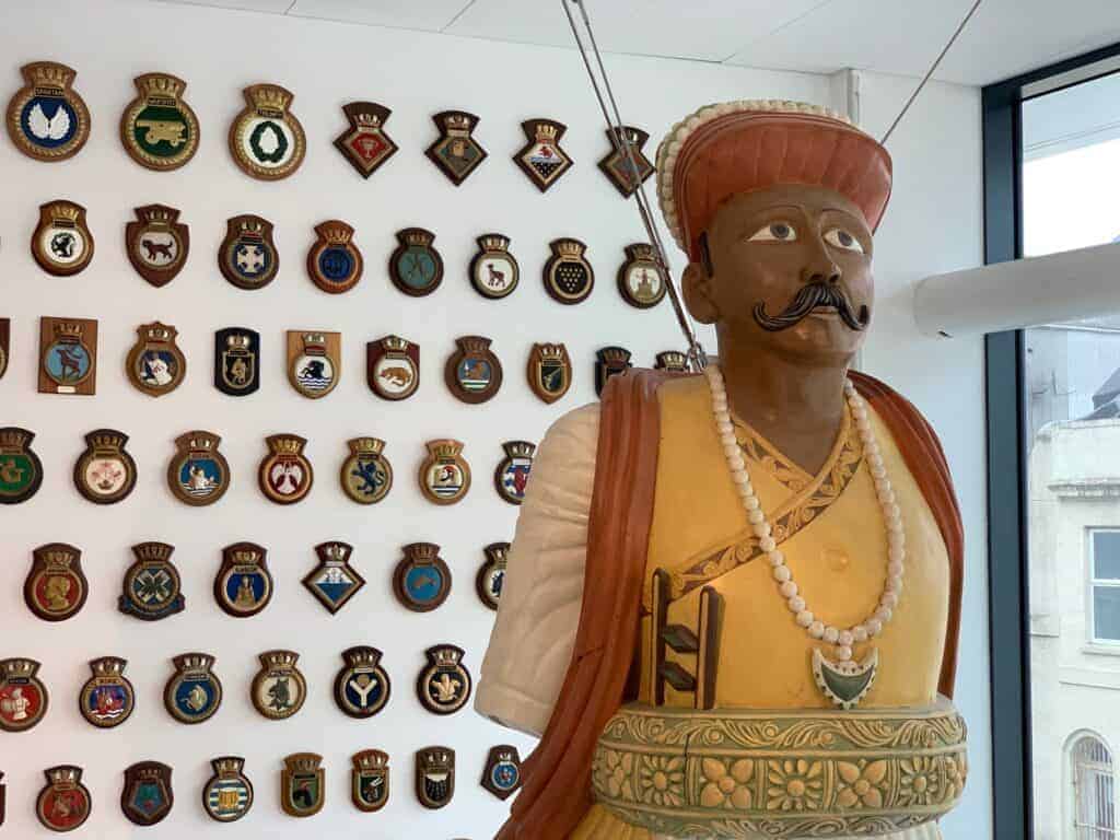 19th Century Royal Navy figurehead hanging in the entrance to The Box with ships crests in background