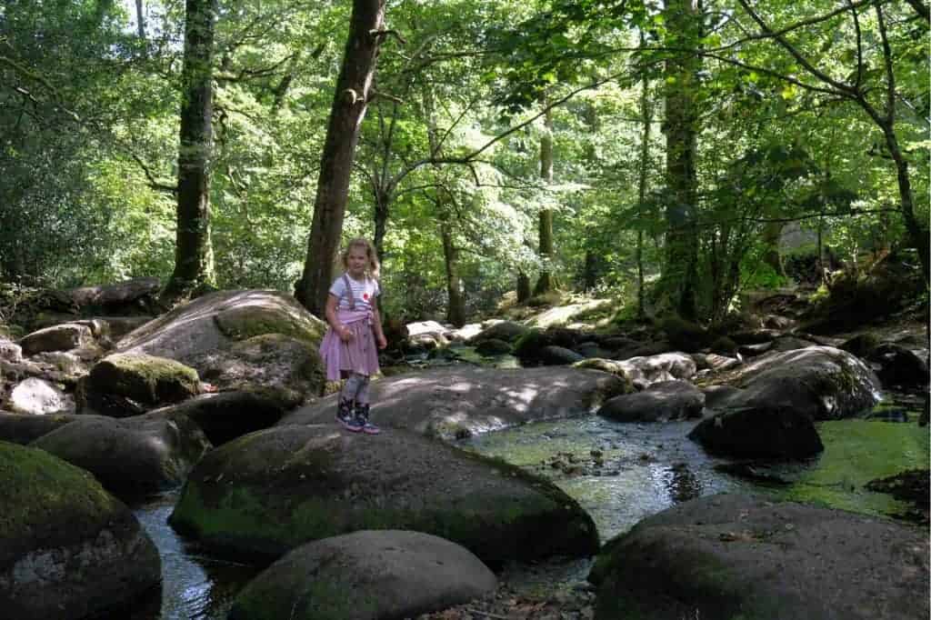 Girl stood on boulder at Becky Falls Devon