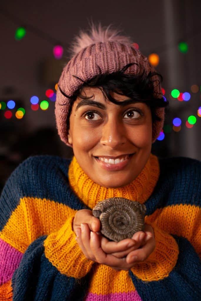Actor playing the role of Rhia holding a fossil