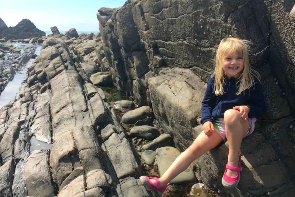 Girl sitting on rocks on Blackpool Mill beach
