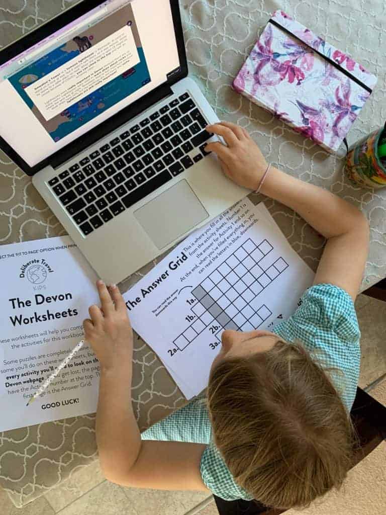 Child sat at laptop using Devon activity book for kids