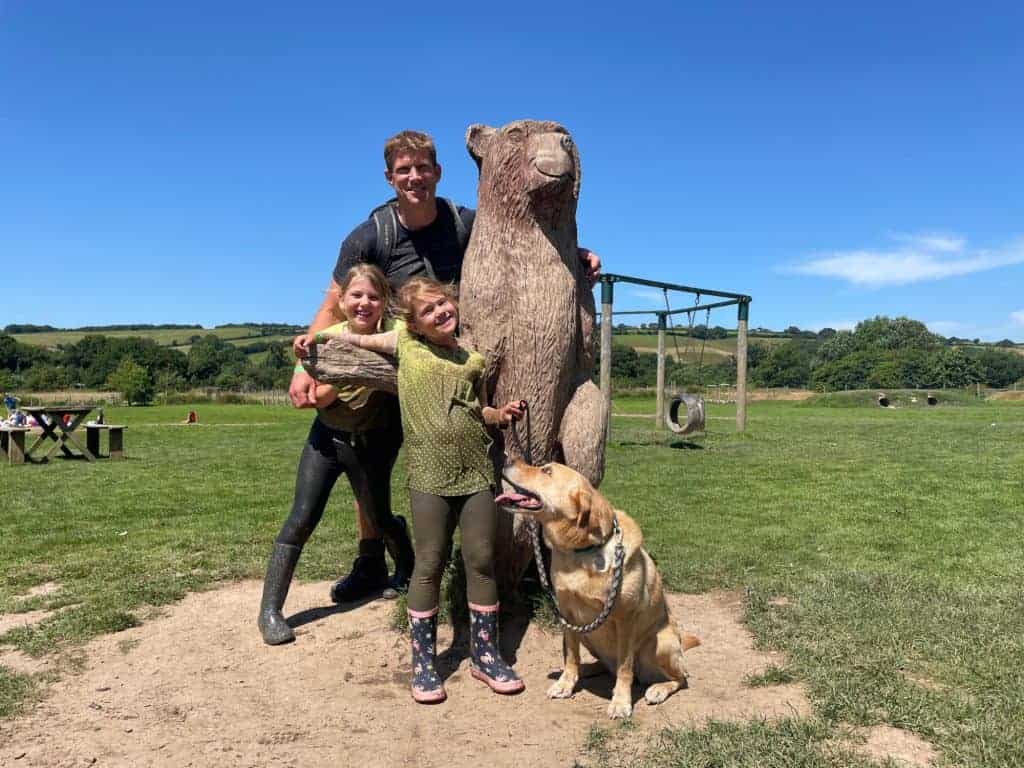 Family and dog with wooden bear sculpture at The Bear Trail