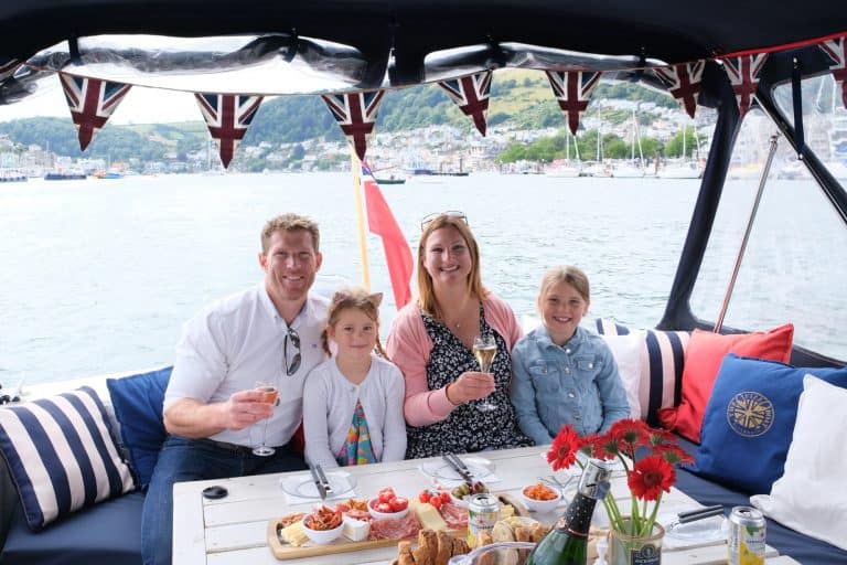 Family sat at the rear of The Fizz Boat with glasses of wine and platters of food