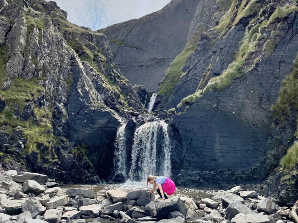 Girl playing on rocks at bottom of Speke's Mill waterfall