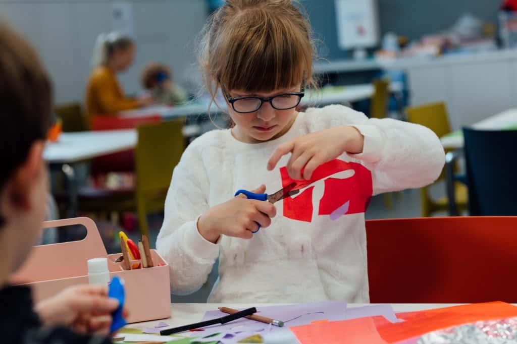Child cutting shapes out of red paper