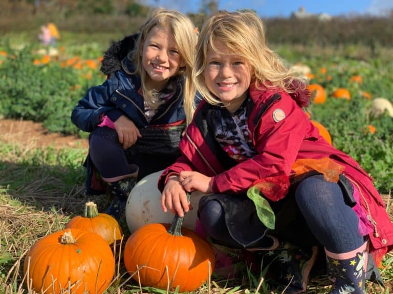 Children crouching over pumpkins in Halloween fancy dress