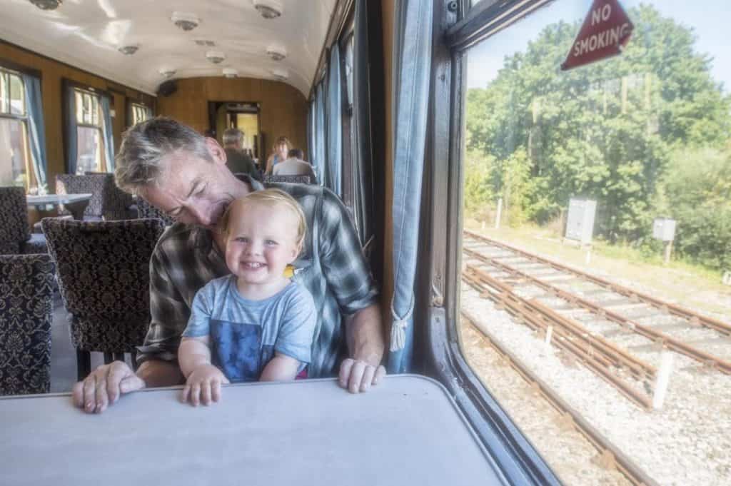 Little boy sat with his dad in train carriage