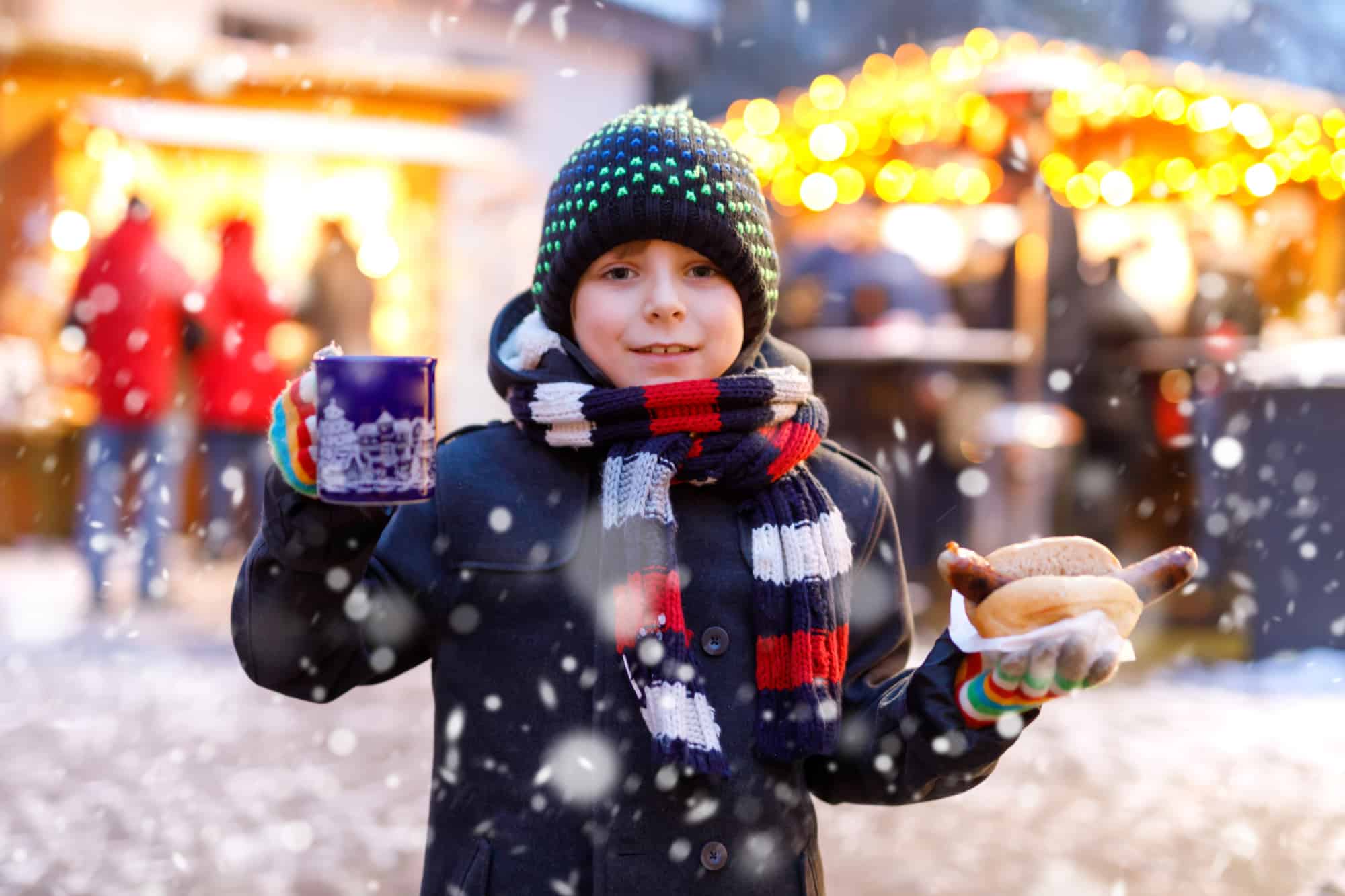 Child with drinks and hot dog at a Christmas market