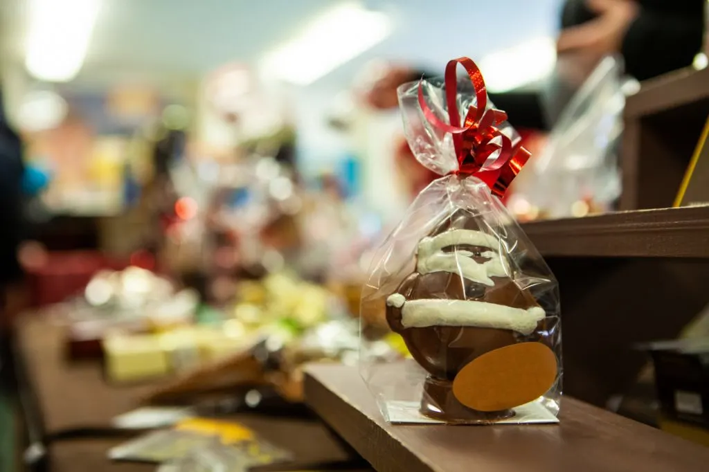 A gift wrapped chocolate Santa Claus with red bow on Christmas market stall
