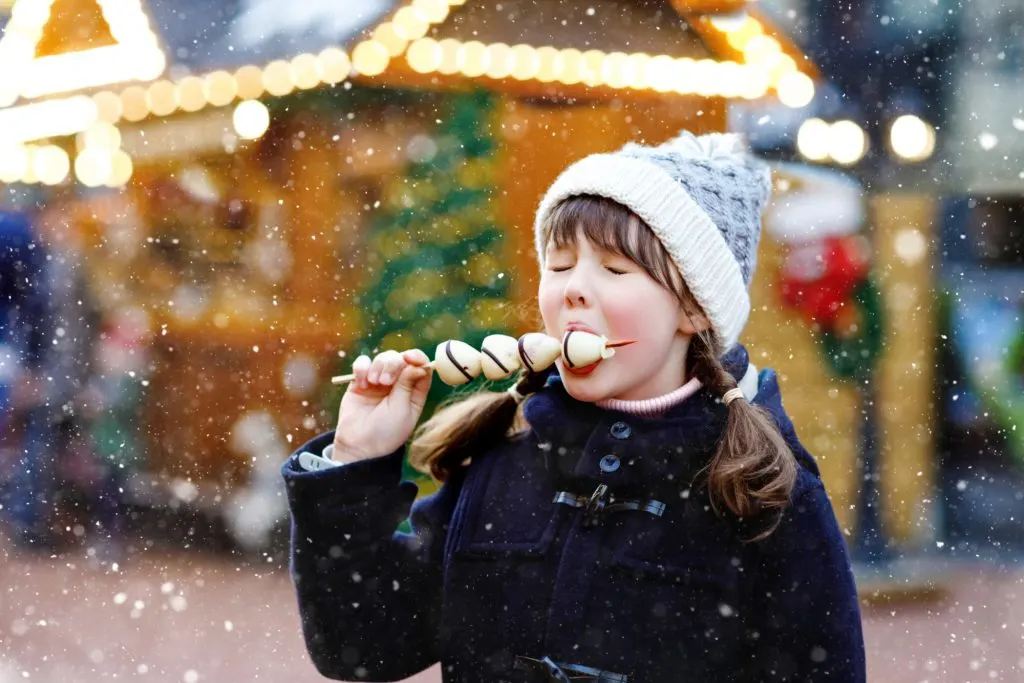 Child eating sweet treat at Christmas market in Devon