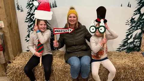 Family holding photo props in front of painted snowy scene