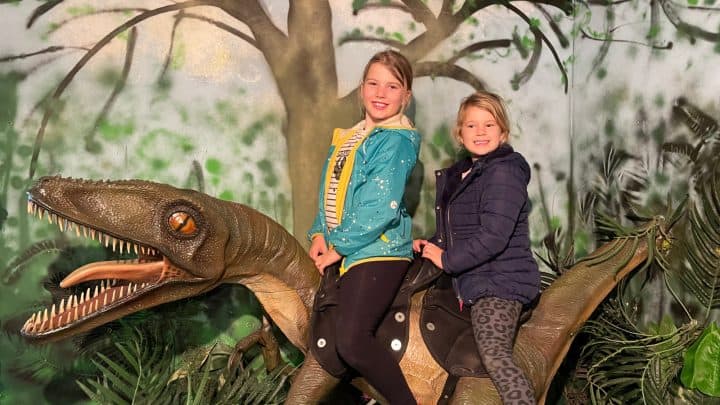 Children sat on the back of a life-sized raptor model