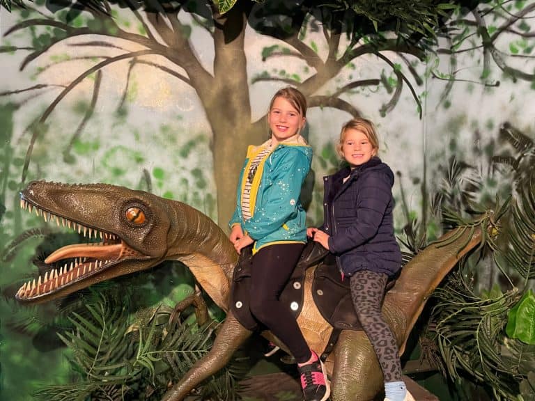 Children sat on the back of a life-sized raptor model