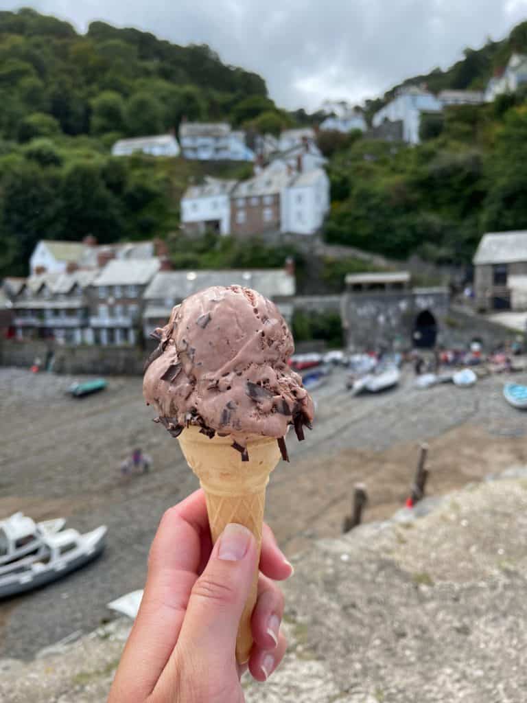 Hand holding ice cream in front of Clovelly Harbour