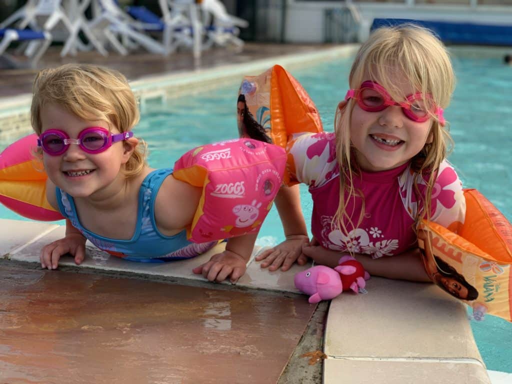 Children wearing goggles and arm bands in a swimming pool