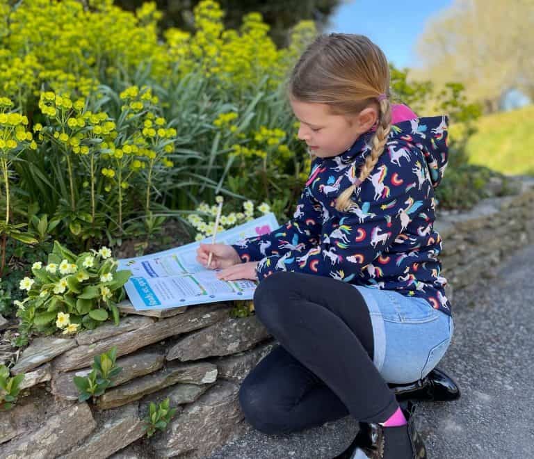 Child filing out Easter trail sheet in garden