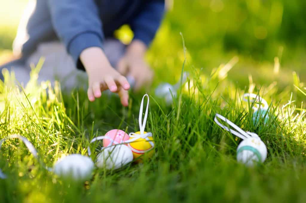 Child's hand reaching for Easter eggs in grass