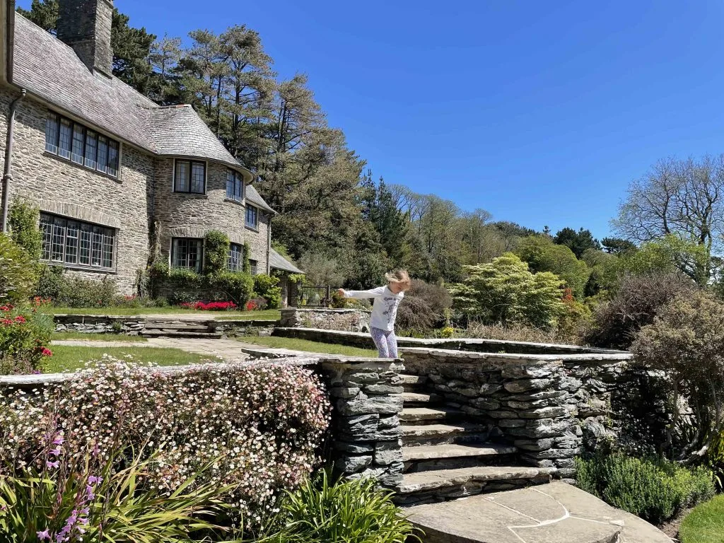 Child jumping down steps in front of Coleton Fishacre house
