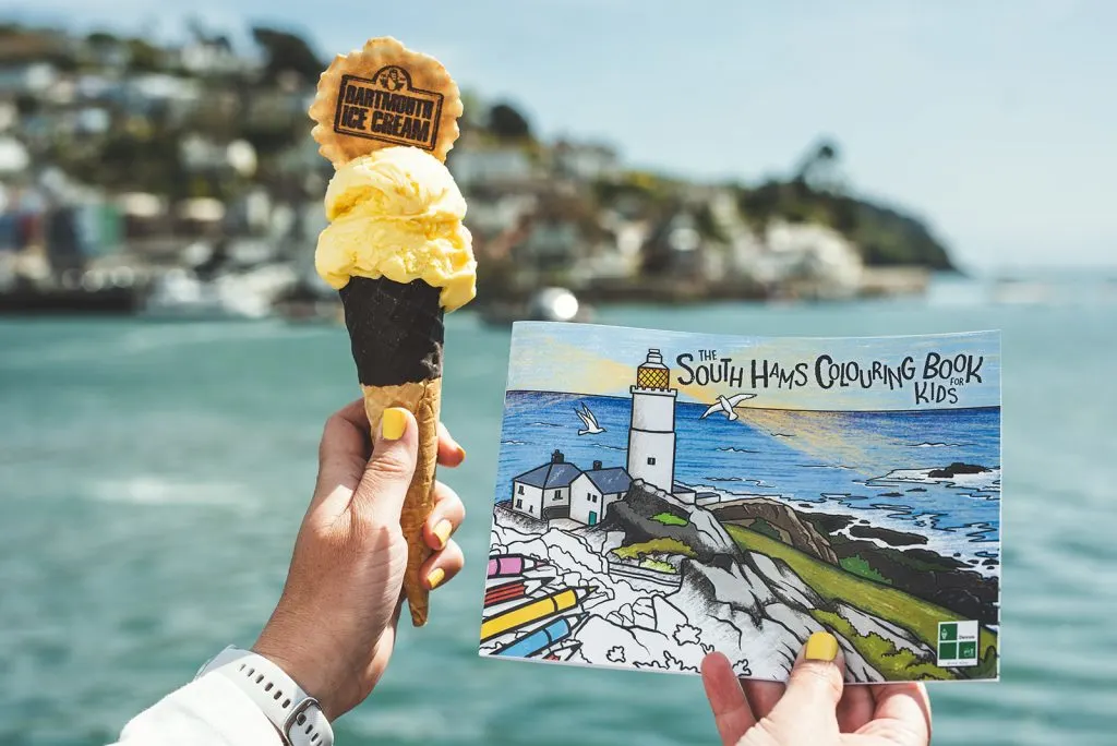 South Hams colouring book bing held up with an ice cream in front of River Dart view