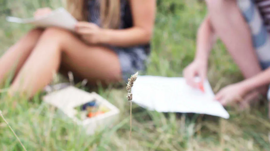 Children studying a blade of grass in field
