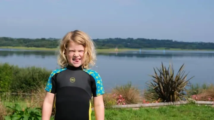 Child in wetsuit stood in front of Roadford Lake
