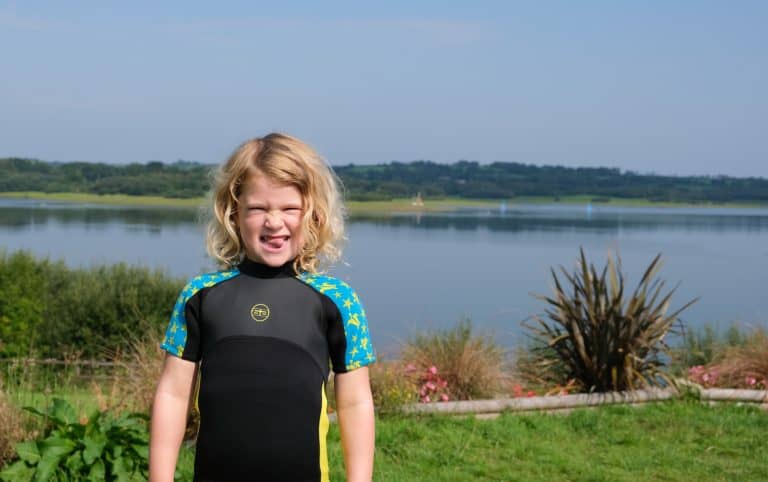 Child in wetsuit stood in front of Roadford Lake