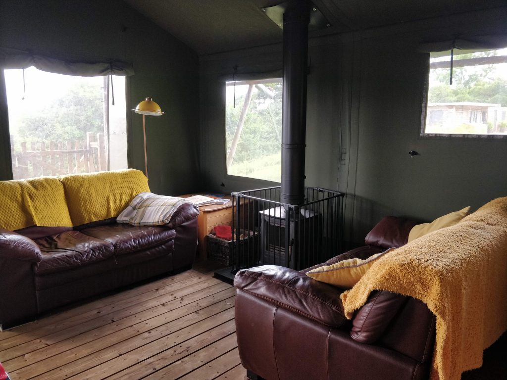 Sofas and wood burner in living room of safari tent