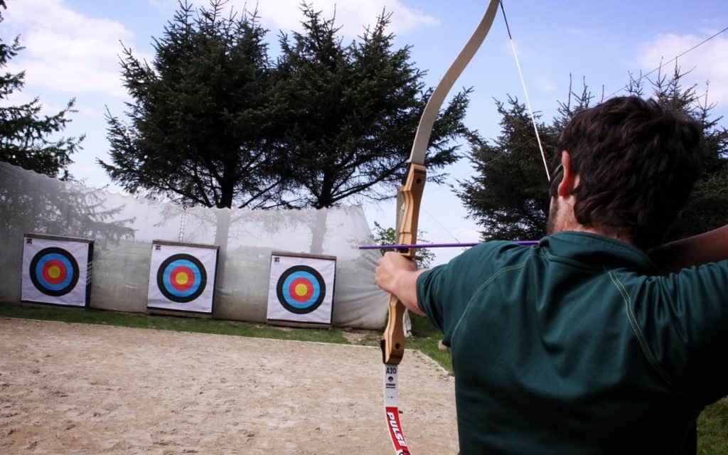 Young man shooting target on Archery range at YHA Bracken Tor