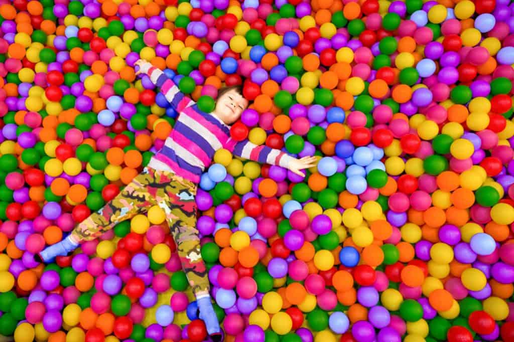 Boy laying in ball pit of brightly coloured balls