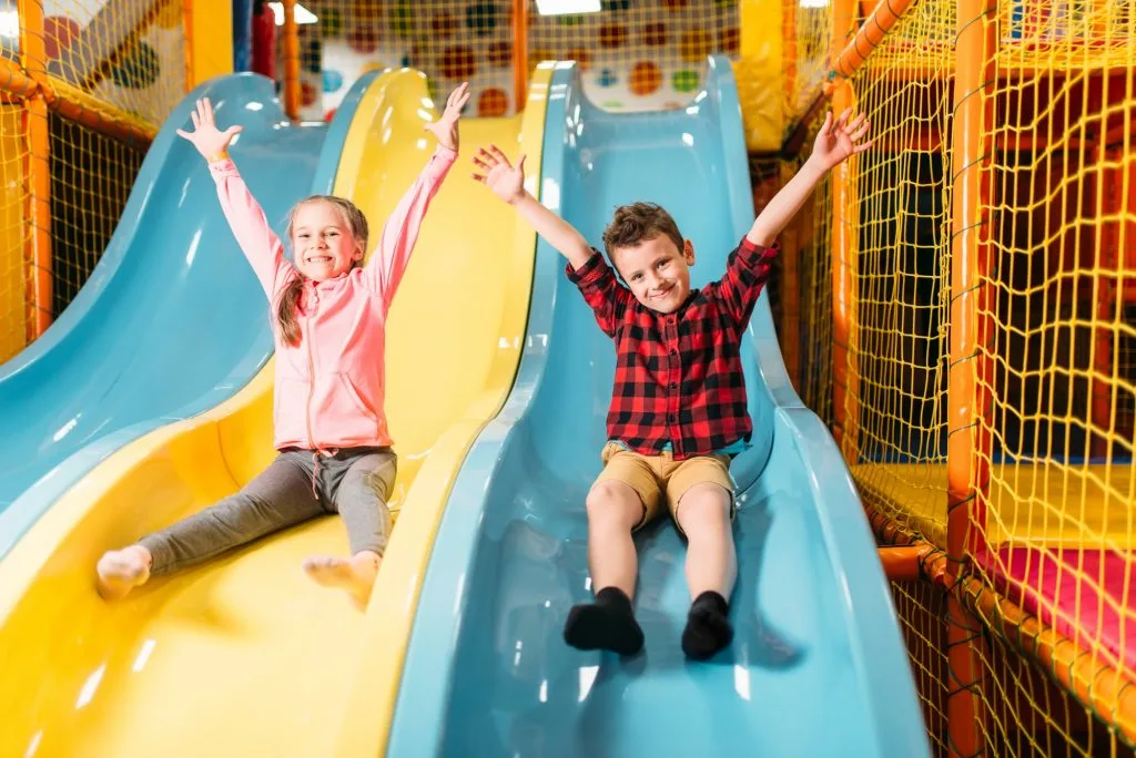 Children sliding down yellow and blue slide in soft play in Devon