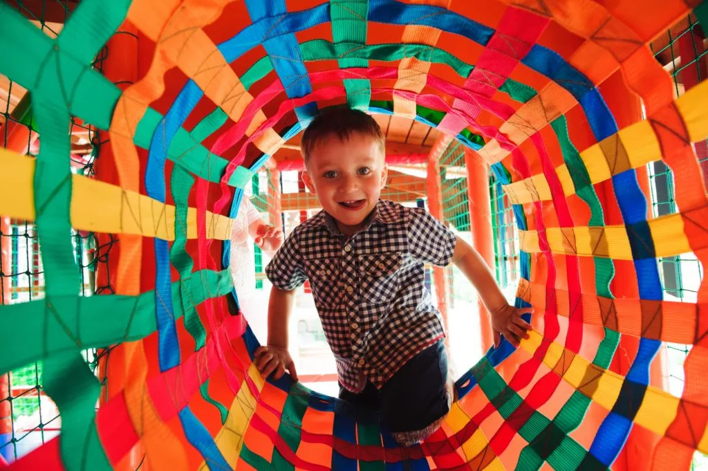 Boy playing in fabric tunnel at soft play centre