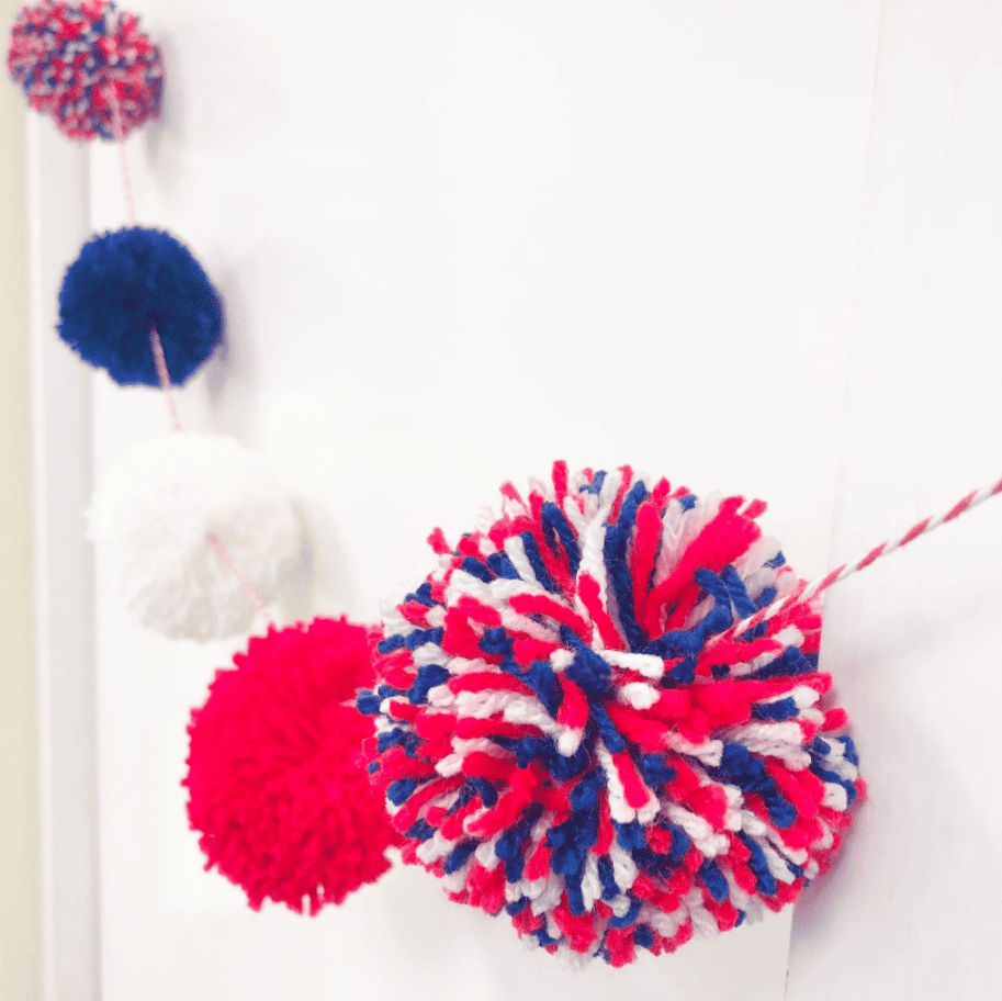 Red white and Bly pom poms strung on a garland