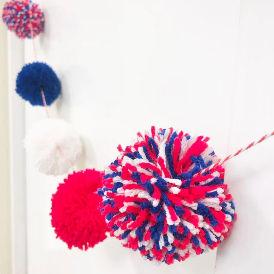 Red white and Bly pom poms strung on a garland