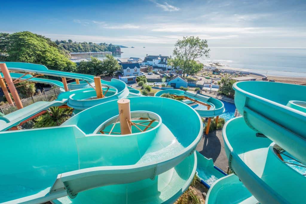 View of Goodrington Sands beach over the top of looping blue watersides at Splashdown Quaywest in Devon