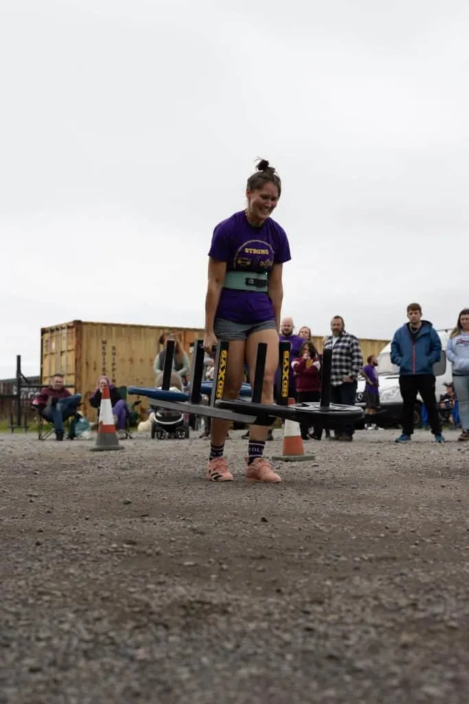 Woman holding weighted bar takes part in strong woman competition