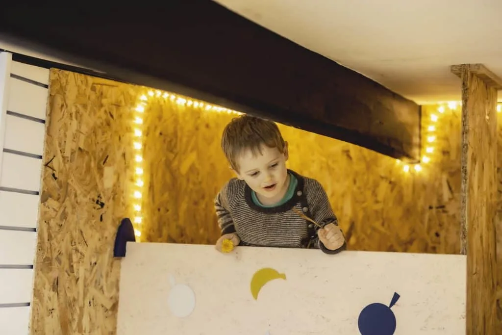 Young boy looking over the top of a wooden play house