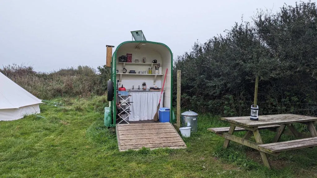 A view of the inside of the converted horse box with a Kitcheners since, shelves, cool box and broom