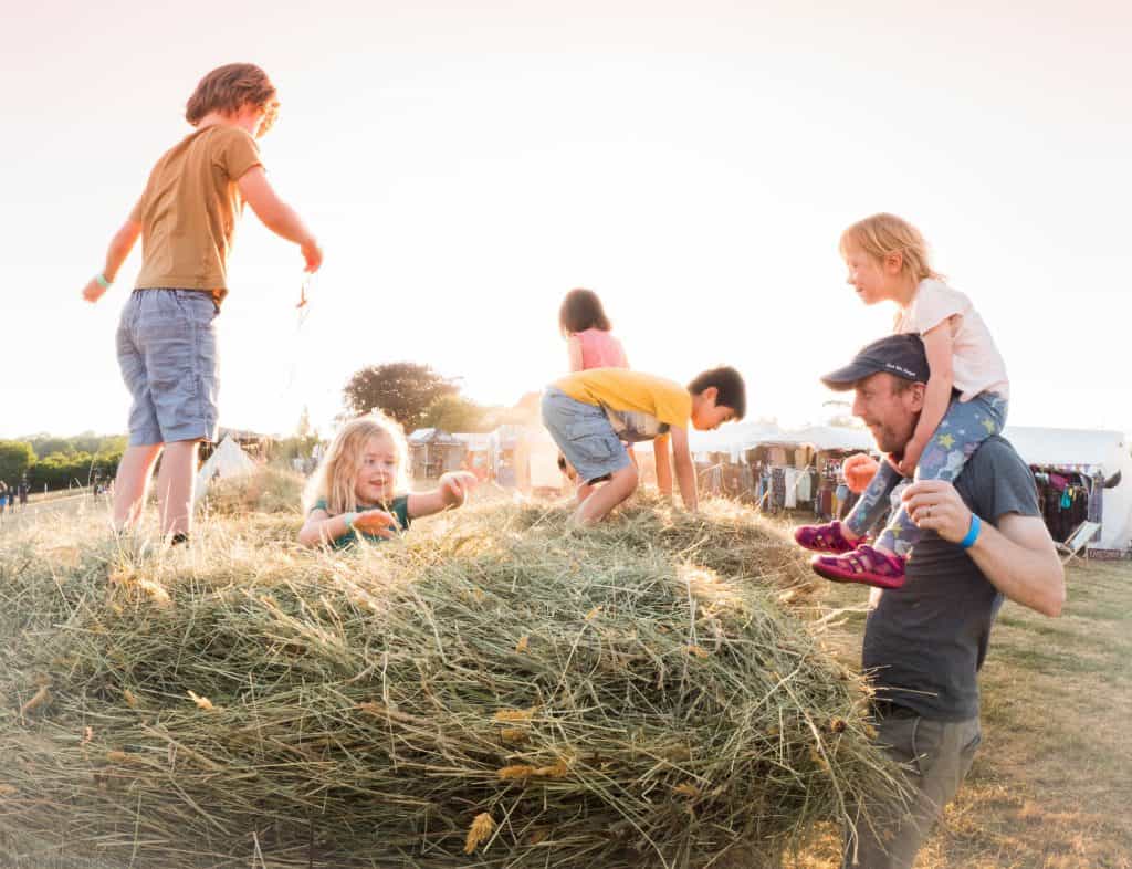 A group of children play in a hay bale on a sunny summer's day